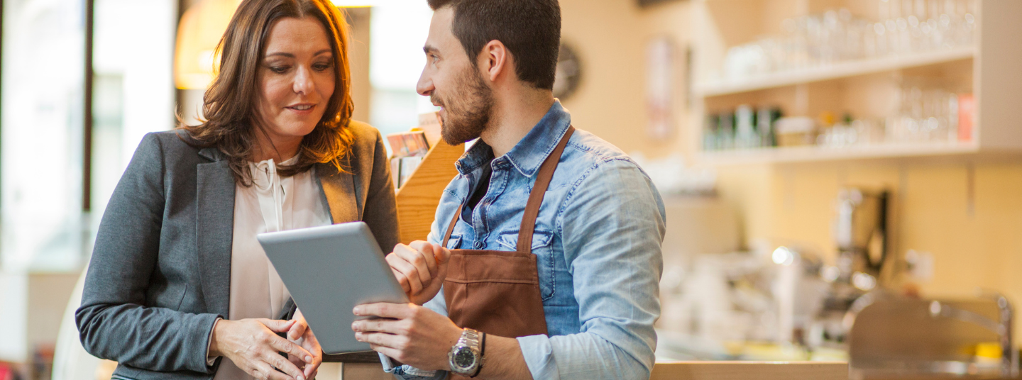 Mitarbeiter aus dem Service eines Cafés unterhält sich mit einer Kundin