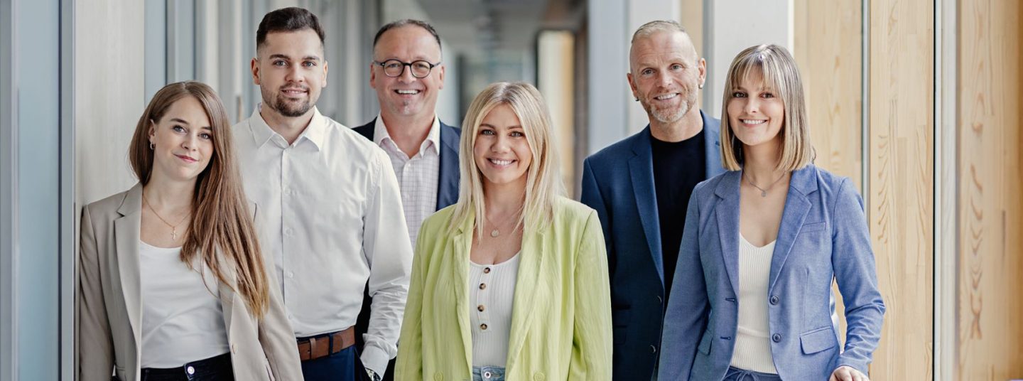 Mitarbeitende der AutoVision in Businesskleidung lächeln in die Kamera.