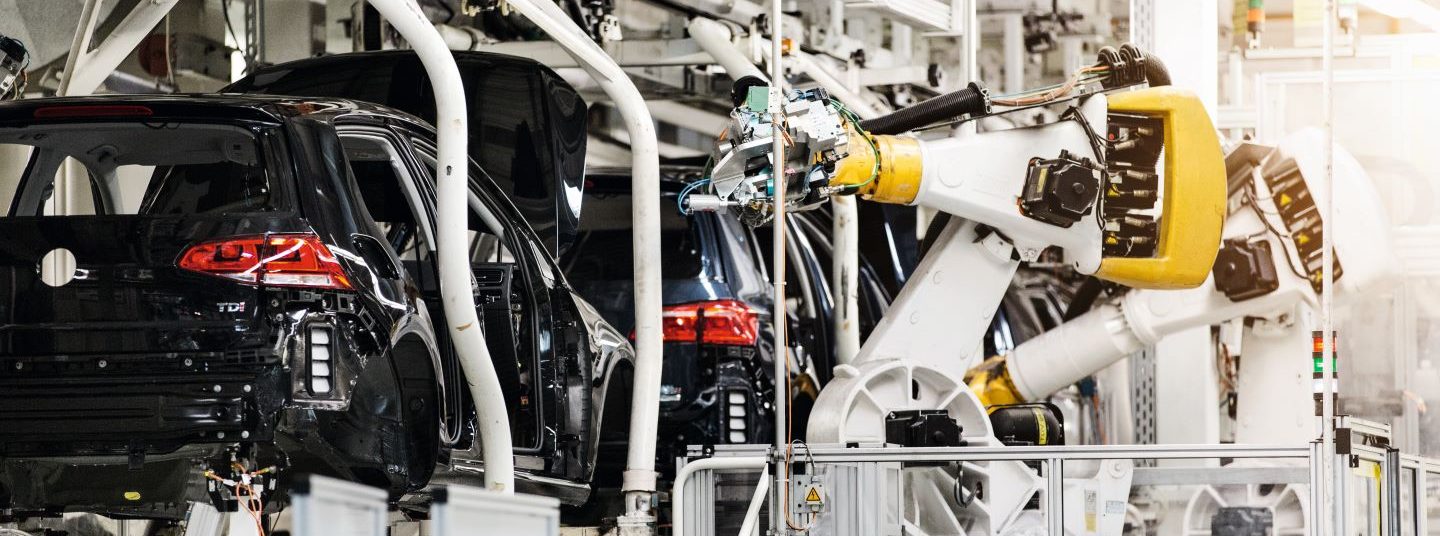 Ein Roboter bearbeitet Fahrzeuge während eines Fertigungsschritts in der Automobilproduktion bei Volkswagen