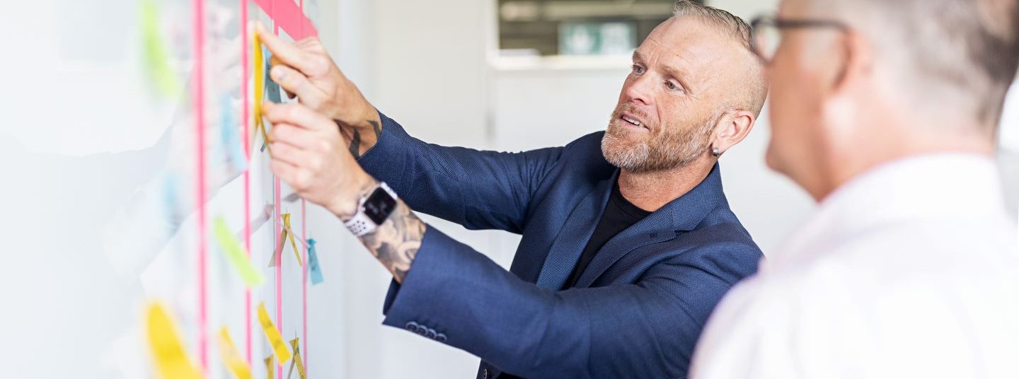 Mitarbeitende der AutoVision stehen vor einem Scrum Whiteboard